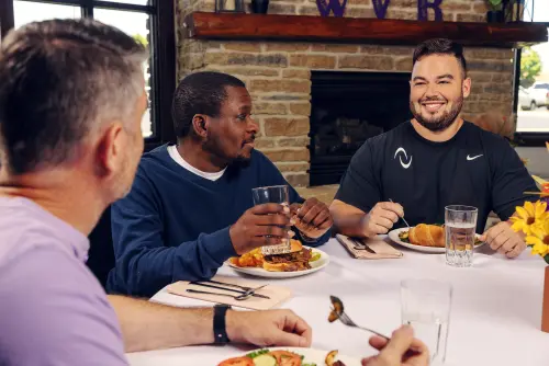 Men having lunch and discussing at Wood Violet Recovery.