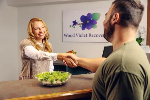 Receptionist greeting a client with a handshake at the reception of Wood Violet Recovery.